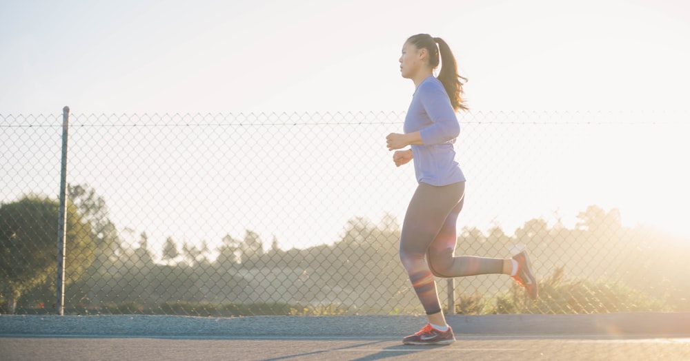 donna che fa jogging vicino alla recinzione metallica