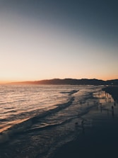 Scenic beach view with sunset and a group enjoying a bonfire.