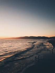 Scenic beach view with sunset and a group enjoying a bonfire.
