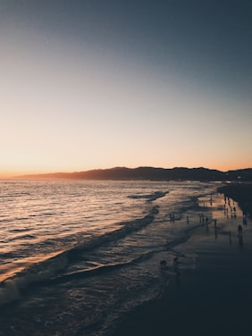 A scenic view of a traveler enjoying a sunset at a beach.
