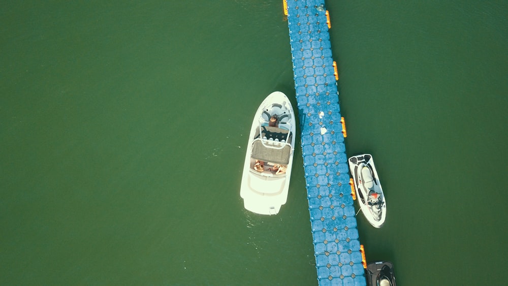 two white speedboats on body of water beside blue dock