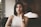 woman wearing gray spaghetti strap shirt sitting on black leather sofa close-up photo