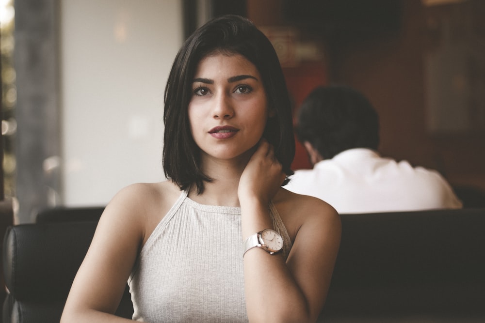 Femme portant une chemise grise à bretelles spaghetti assise sur un canapé en cuir noir photo en gros plan