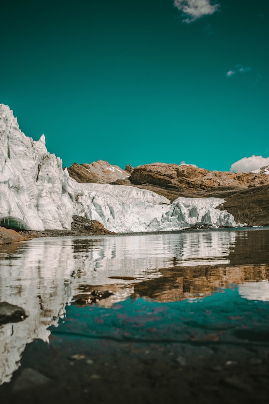 rocky mountains near body of water during daytime in Huascaran Peru