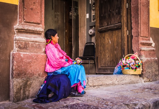 woman sitting on gray pavement leaning on brown wall in San Miguel de Allende Mexico