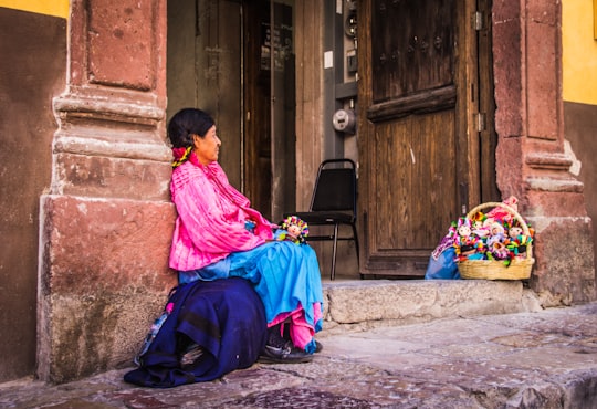 woman sitting on gray pavement leaning on brown wall in Santiago de Querétaro Mexico