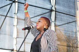 woman in black and gray striped cardigan raising her hand
