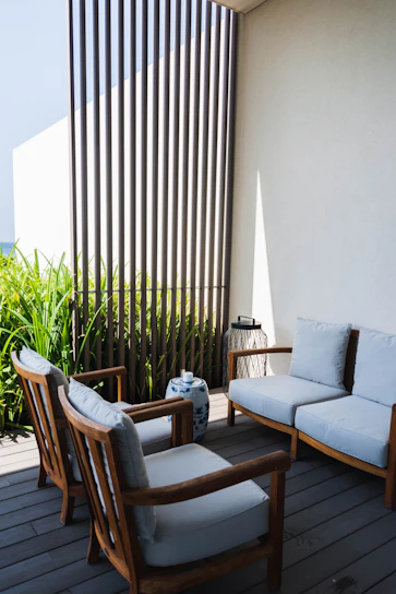 Cozy outdoor loveseat with colorful cushions beside a wooden bar cart on a sunny patio.