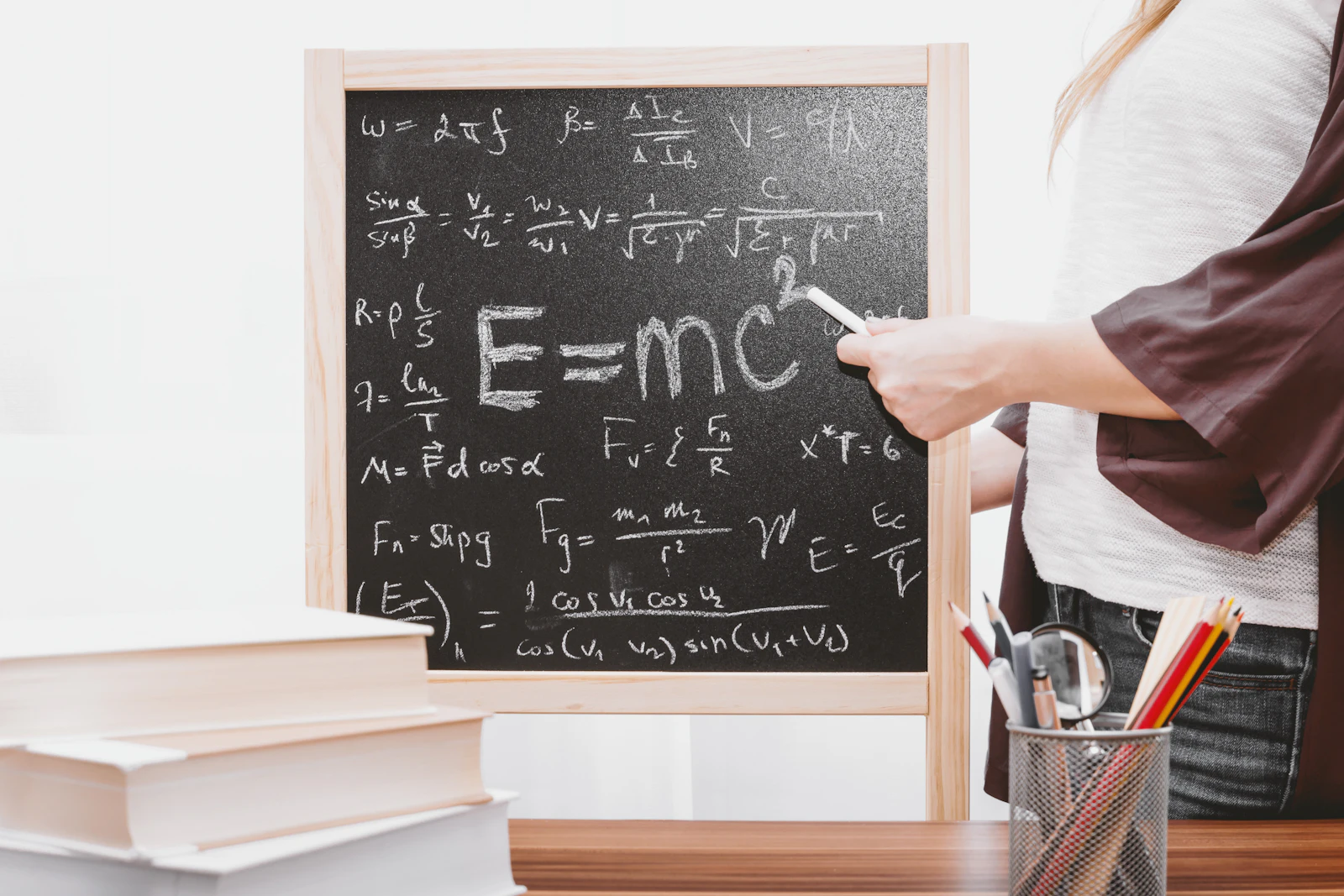 Instruktor kredom piše formulu E=mc² na školskoj ploči punoj fizikalnih formula