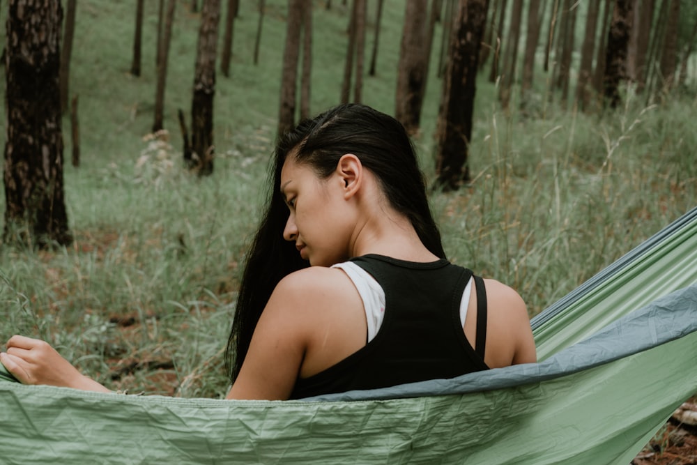 woman in black top sitting on green hammock