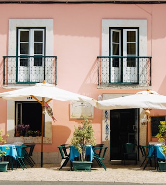 two white patio umbrellas near pink and white painted concrete building