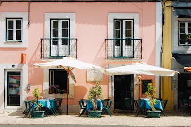 two white patio umbrellas near pink and white painted concrete building