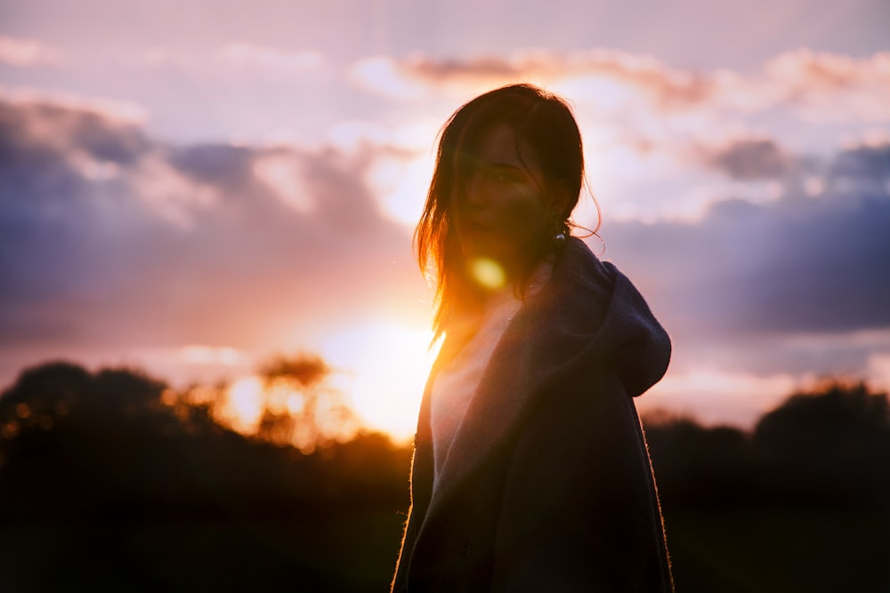 Mujer con sudadera con capucha gris durante la puesta del sol