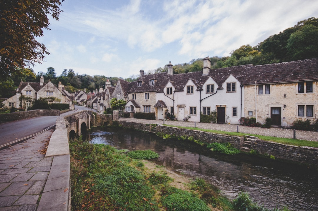 View of the bridge and up the high street Cotswolds cottages in Castle Combe Village, Wiltshire, UK – best Castle Combe walks - Photo by Ivy Barn | Castle Combe England