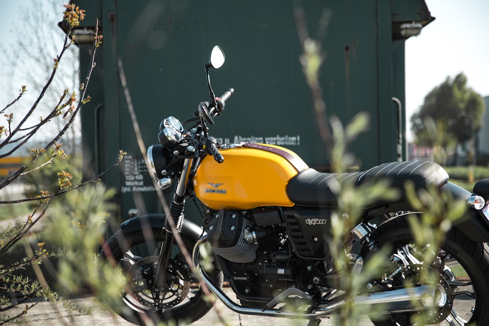 Moto standard jaune et noir près du mur vert