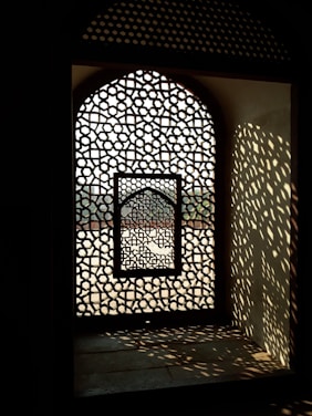 Close-up of a beautifully patterned terracotta jali casting intricate shadows on a sunlit wall.