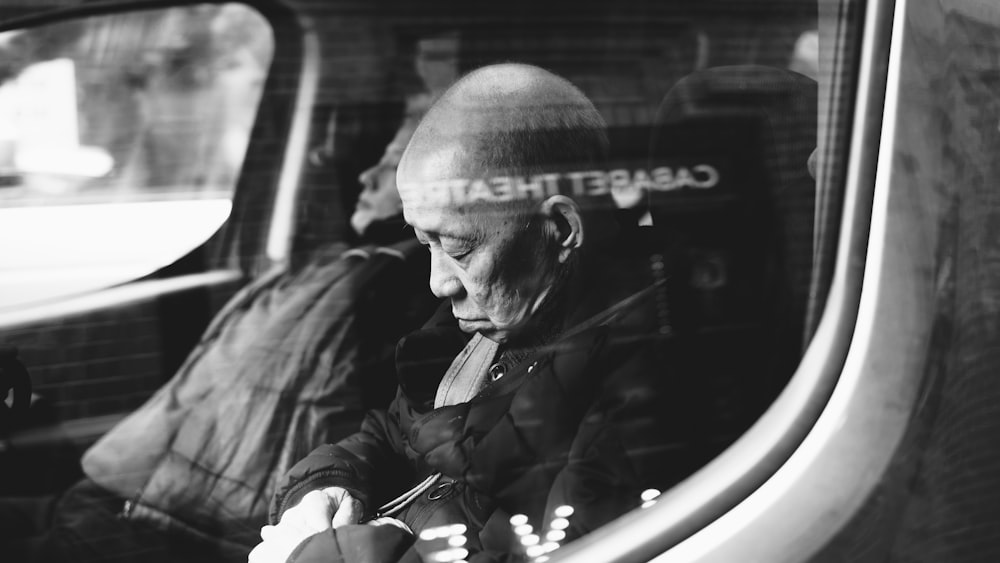 grayscale photo of man inside vehicle sleeping