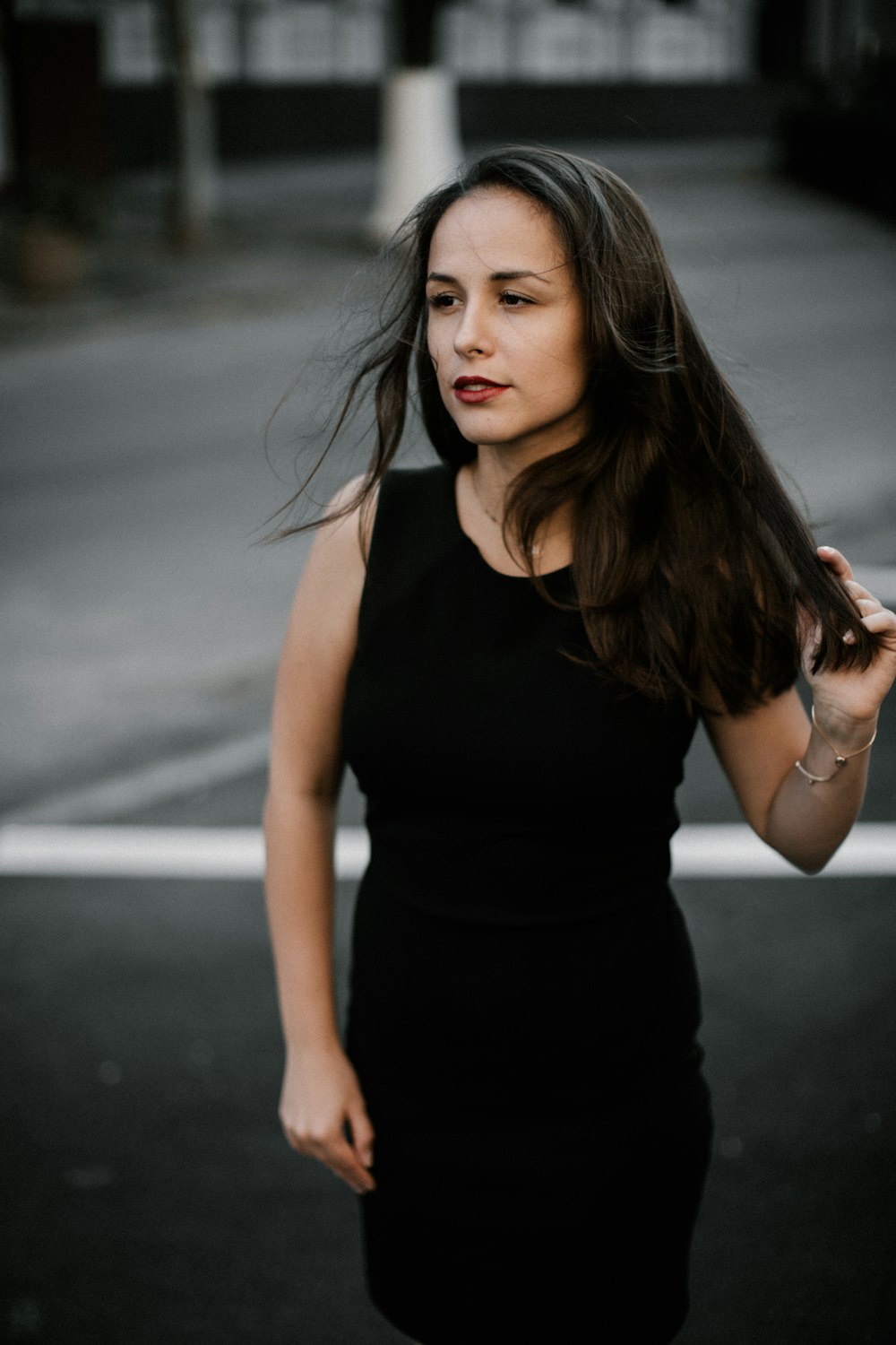검은 민소매 드레스를 입은 여자가 길을 걷는 포커스 사진