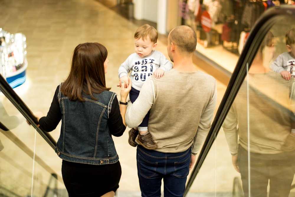 man, woman, and child standing on escalator