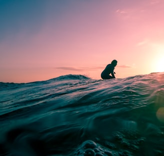 man surfing on ocean water during golden hour