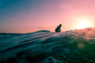 man surfing on ocean water during golden hour