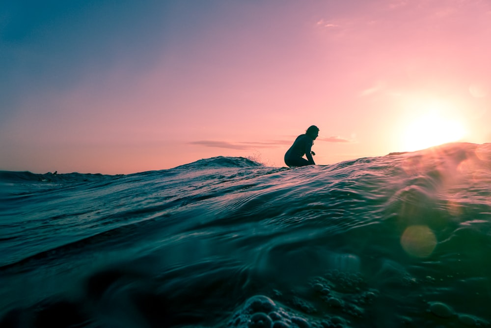 Uomo che fa surf sull'acqua dell'oceano durante l'ora d'oro