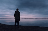 silhouette of man standing near body of water