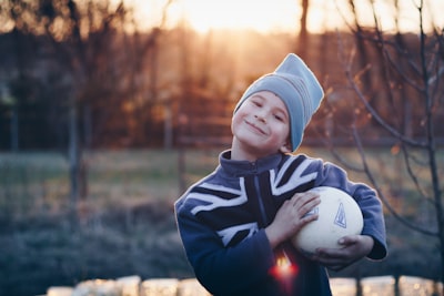 boy holding a ball proud teams background