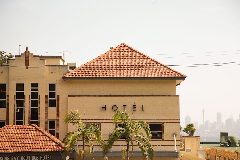 photo of brown concrete Hotel with two coconut trees