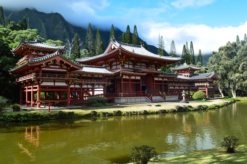 red wooden framed temple near body of water during daytime