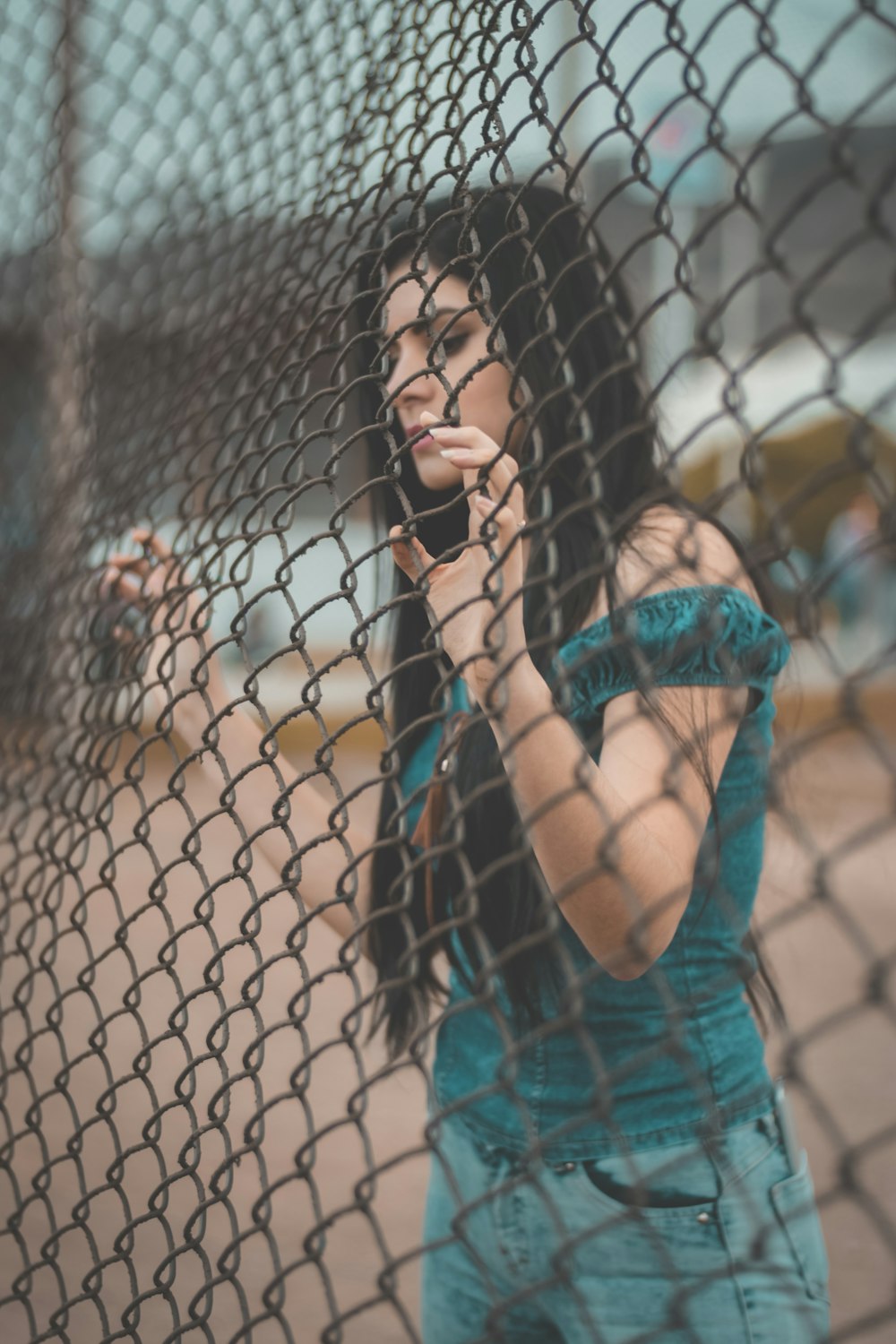 灰色の金属柵に触れる女性の写真