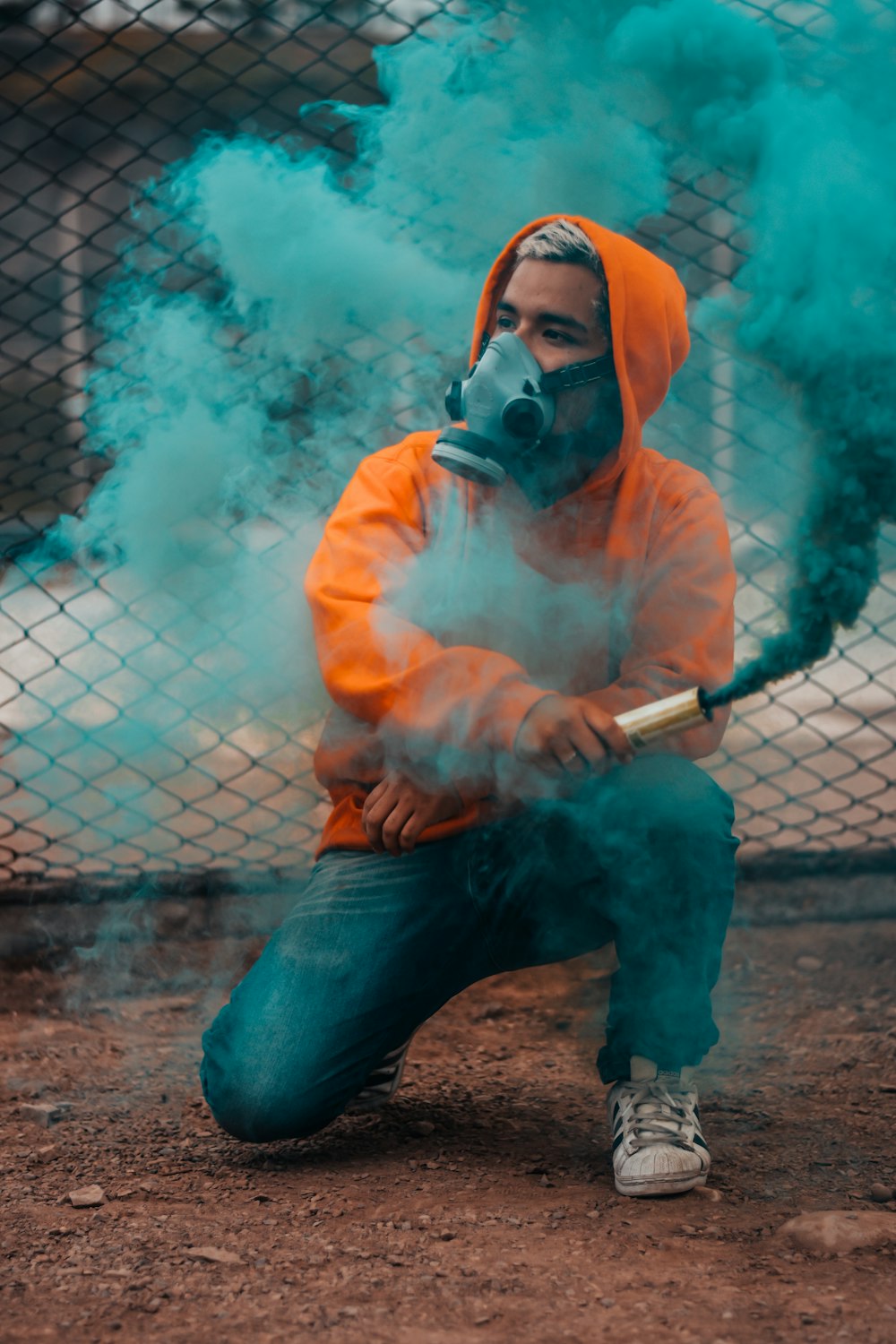 hombre sosteniendo el tubo con humo verde durante la foto diurna