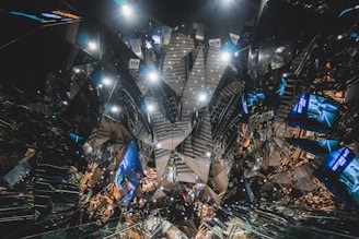A complex, futuristic interior design featuring reflective surfaces and angular patterns creating a kaleidoscopic effect. Various advertisements and lights are visible, adding to the vibrant and chaotic atmosphere.