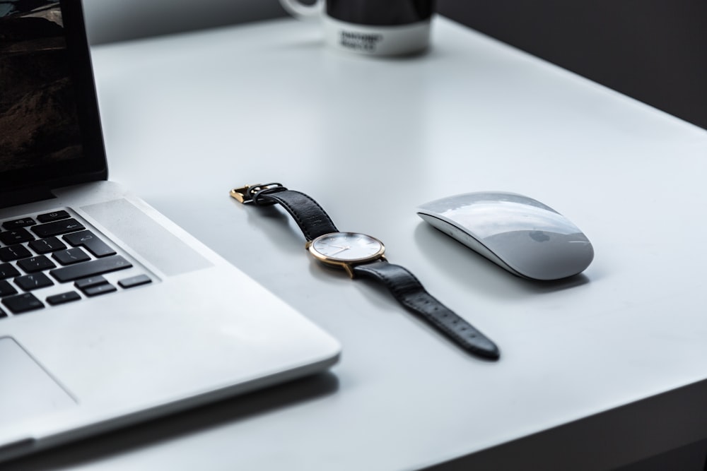 테이블 위의 Apple Magic Mouse 옆에 있는 둥근 흰색 아날로그 시계