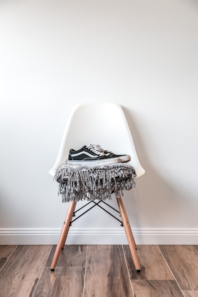 pair of black low-top Vans sneakers on white chair