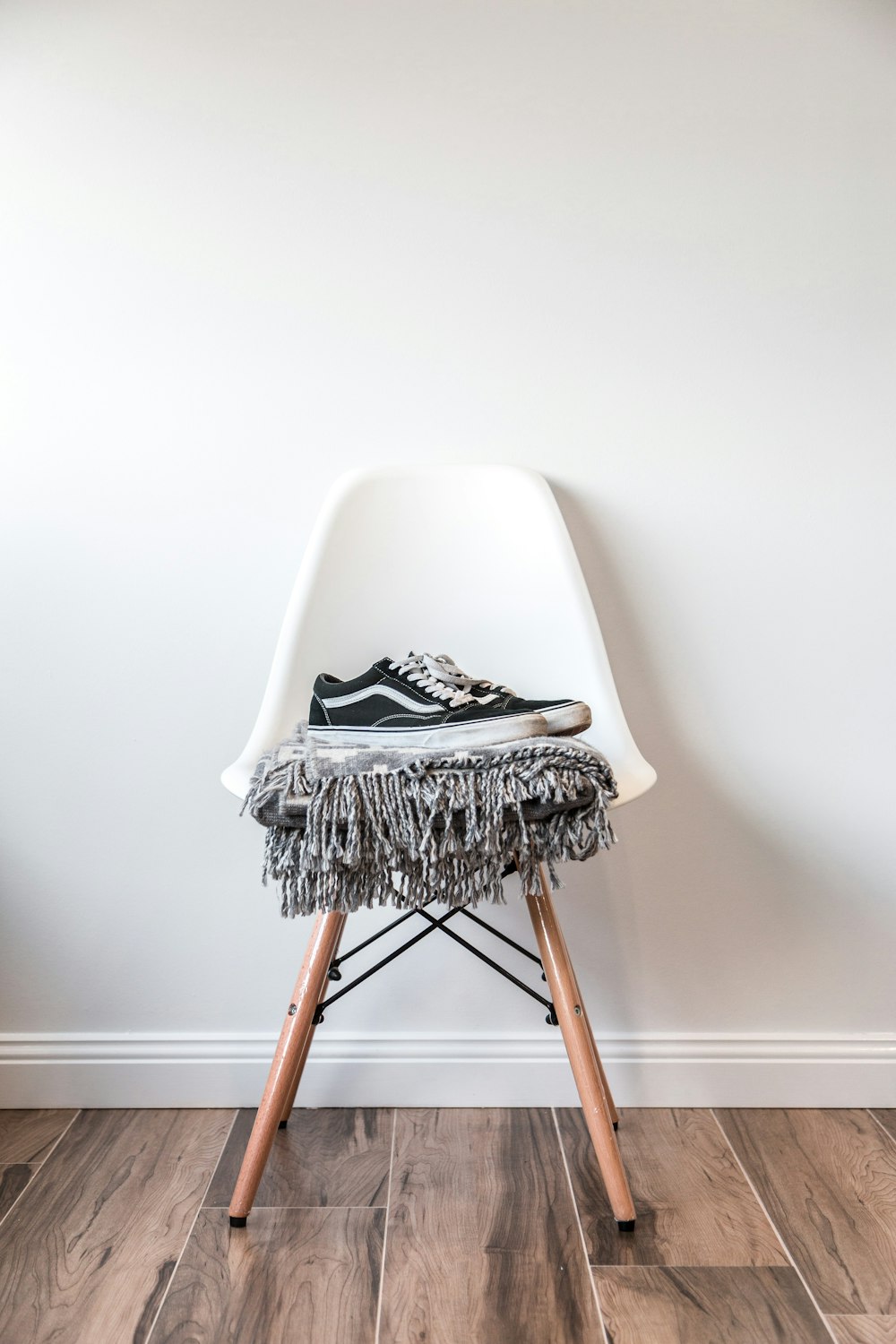 pair of black low-top Vans sneakers on white chair