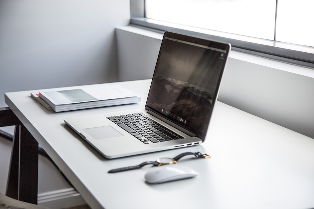 MacBook Pro near watch and Apple Magic Mouse