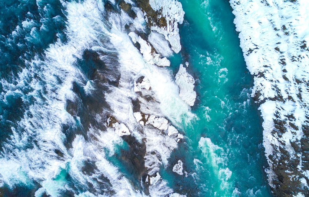 top view photography of green water river beside stones covered with snow at winter