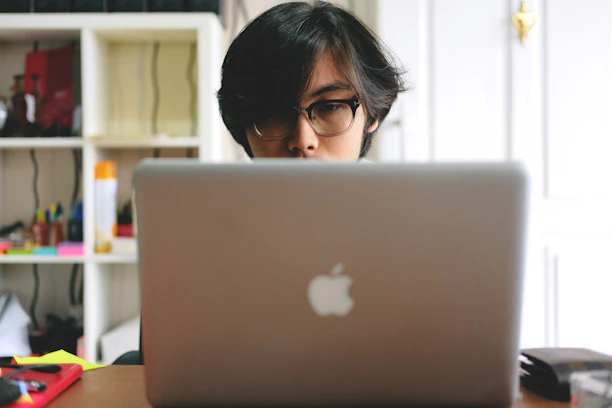 A focused student working on a laptop with colorful educational materials around.