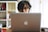 A focused individual working on a laptop surrounded by books and notes related to IT training.