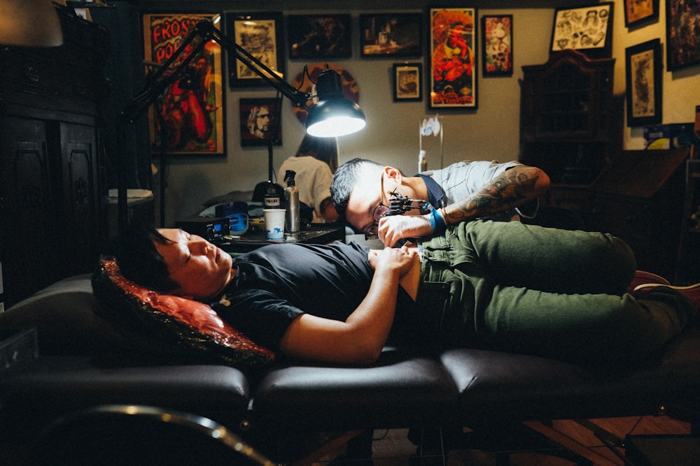 man in gray polo shirt tattooing a man