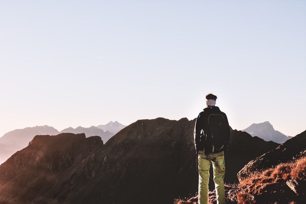 uomo in piedi davanti al paesaggio marrone della montagna durante il giorno