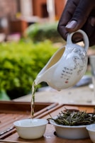 Close-up of golden herbal oil being poured into a small ceramic bowl.