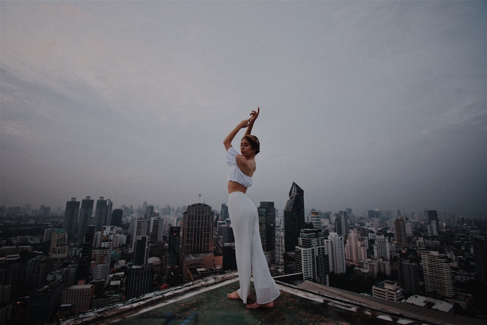 Donna in crop top bianco e pantaloni in piedi sul tetto