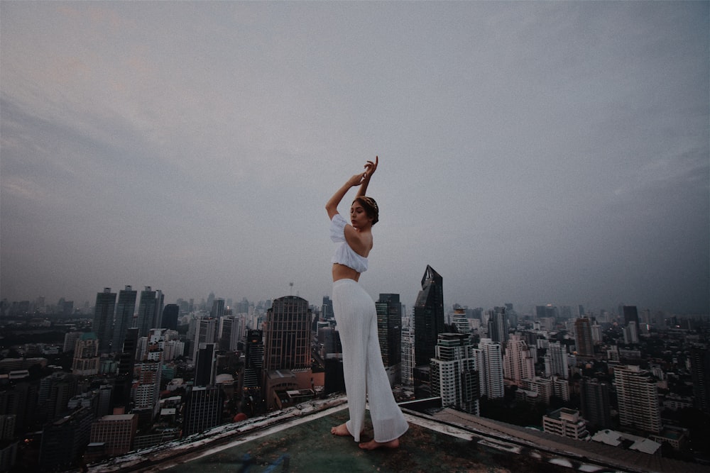 woman in white crop top and pants standing on roof