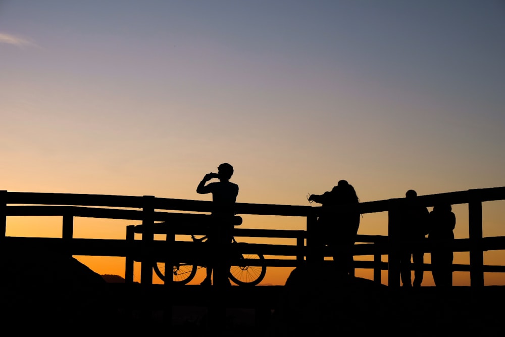 Silhouettenfoto von Personen, die Fotos von Sonnenuntergang machen