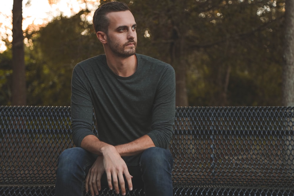 man sitting on black metal bench