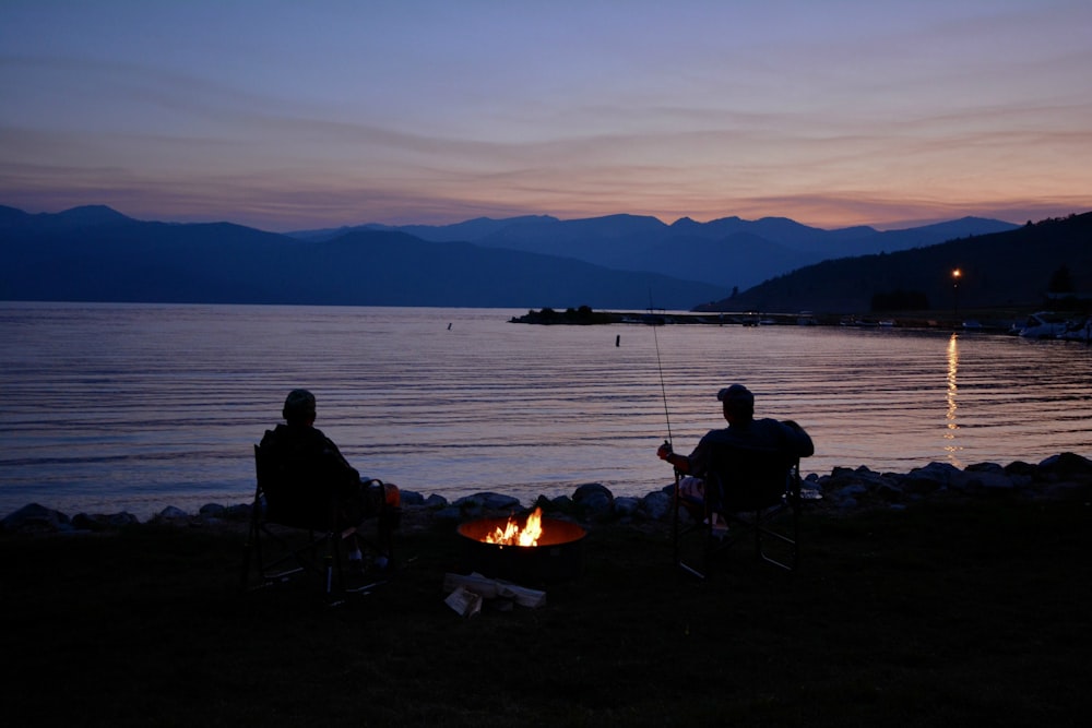 silhouette de deux hommes à côté d’un plan d’eau calme