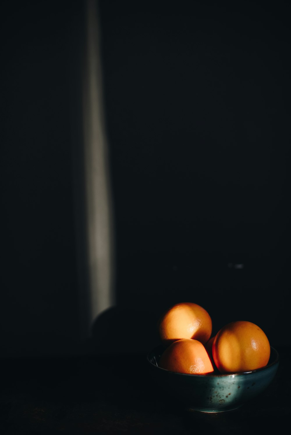 three orange citrus fruits with bowl