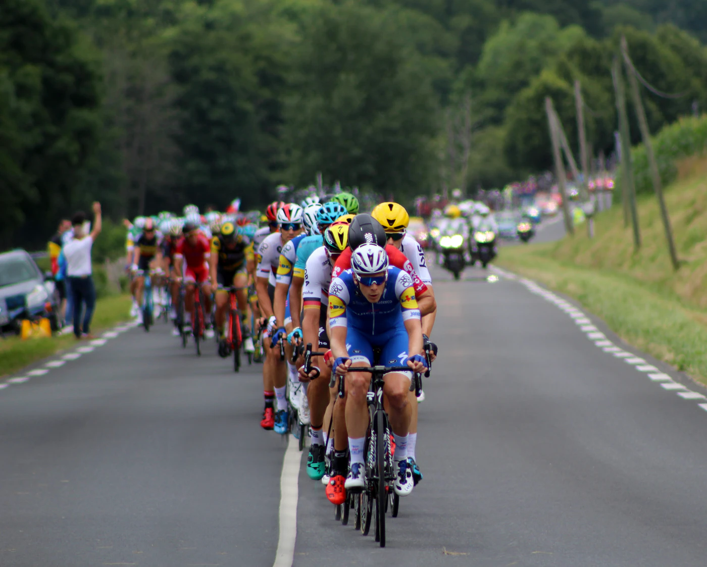 A large bunch of racing cyclists on a road, seen from behind